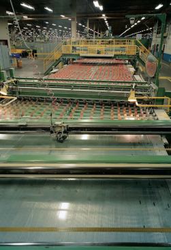 Next, it passes under automated cutters that score it into preprogrammed widths before cutting it lengthwise. The cutting blades are computer-adjusted to fulfill the specified dimensions for different sizes of prefabricated glass sheets.

