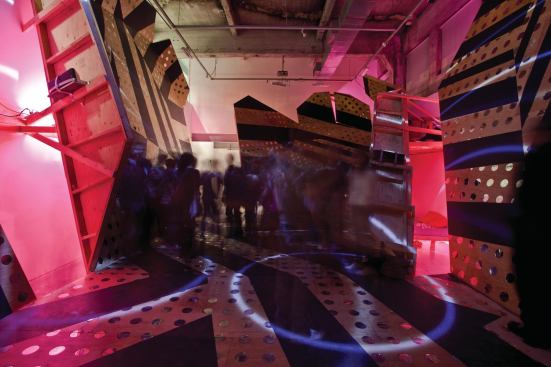Installed in the school's 20-foot-tall main gallery, Silent Disco uses plywood, mirrored plexiglass, and paint to transform the space into a pop, disorienting, and immersive environment.