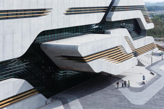 On the north face of the building, the projecting volume of the médiatheque cantilevers over the main entrance. The paving pattern echoes the geometry of the façade.