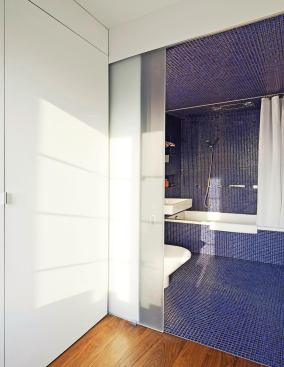 The new bathroom features blue tiles and frosted glass doors.
