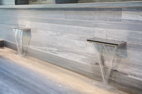 A carved stone lavatory cantilevers from the tiled wall.