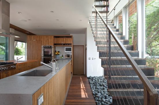 Two long counters serve as the room’s work surfaces. The steel stair casts a “shadow” of smooth stones.