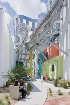 The skin is supported by a series of columns and supports attached to the building, which can be seen most clearly in the courtyard between the event space and clinic.