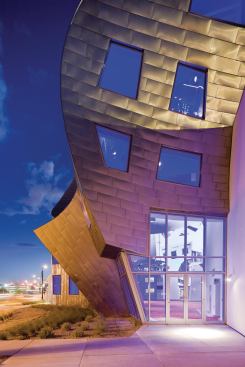 As it meets the ground, the skin peels away to reveal larger windows and entry doors.