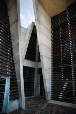 Gum-pole trellisses cover the building's glazed end walls, such as those around one of the main entries.