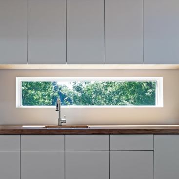 Laminated red and white oak planks make up the kitchen countertops, while the windows offer views of the trees.