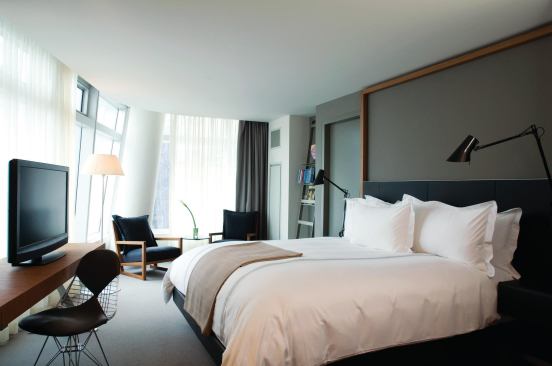 Each guest room features a unique footprint defined by the curved profile of the tower. The clerestory-level lites in the curtain wall are more heavily fritted to help mitigate glare in the rooms when the sun is at its peak. The canted form of a support column is echoed in a ladder bookshelf, holding more of Ortlieb’s beloved volumes.