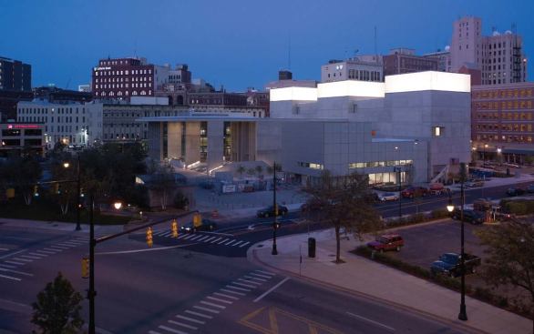 FACING THE CITY

At night, the gallery lanterns (top) make a striking presence on the skyline-lending the quiet building the quality of a civic landmark. Three layers of insulated glass and a layer of scrim material diffuse the light emitted but protect the artwork within. Streets and sidewalks border the museum on three sides, so Yantrasast wanted each building face to nod to its surroundings. Colored spandrel glass softens the building's southern façade, which fronts the administrative offices and classrooms.

A site plan (above) illustrates how the building extends fingerlike projections toward Ecliptic Park. Negative spaces between these wings include a pocket park, outside seating for the museum cafe, and a sculpture court that reaches deep inside the museum. The project also incorporates small green spaces around the perimeter with a water-efficient landscape design.