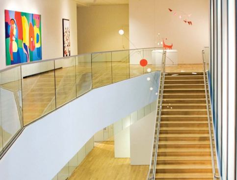 GALLERIES

Visitors reach the galleries along a stair in the East Court. The glass handrail assemblies lend a transparency to the space that makes even narrow walkways seem a part of the larger gallery.

The primary third-floor galleries are crowned by large, glass-enclosed lanterns that filter light from above (facing page). In these spaces, daylight enters through triple-layered glass with ultraviolet protection. Light is further modulated with adjustable louvers and light- filtering shades before bouncing offan inverted-pyramid ceiling and into the gallery space as soft, blended light.