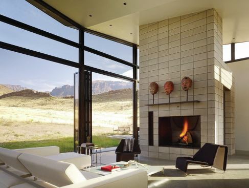 The great room shelters kitchen, living, and dining functions under a canted butterfly roof that rises to open a slice of sky above the jagged horizon.