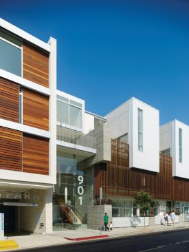 The entrance to the public parking lot, which houses the 156 city-mandated parking spaces, is tucked beside the main entrance. These two access points—vehicular and pedestrian—are located on Hancock Avenue, at the point where the wood shutter-clad two bedroom units give way to the more residentially scaled townhouses and affordable housing apartments.