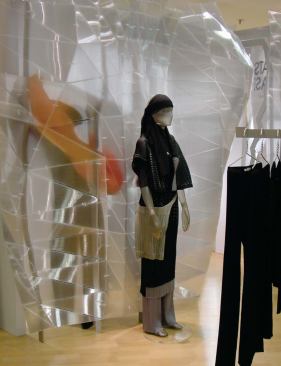 Pleats Please, Issey Miyake, Berlin - After final installation, the faceted wall blends reflections from the room and filtered light from behind. The effect is multiplied by the addition of Miyake’s clothes. Zip-ties also attach the polycarbonate to the frame.