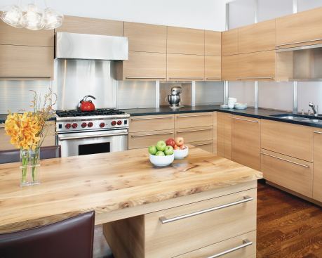 Quartersawn red elm cabinets contrast with the room’s cooler elements: white walls, glass panels, and stainless steel appliances and hardware. 
