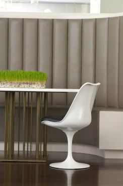 The vertical lines of a custom leather banquette are echoed in the elegantly slim legs of the round breakfast table.