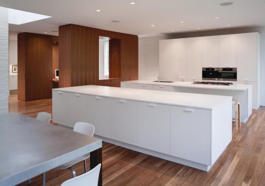 The smooth opalescence of Corian casework in the kitchen, mudroom, and bath is a textural counterpoint to the white brick and plaster.