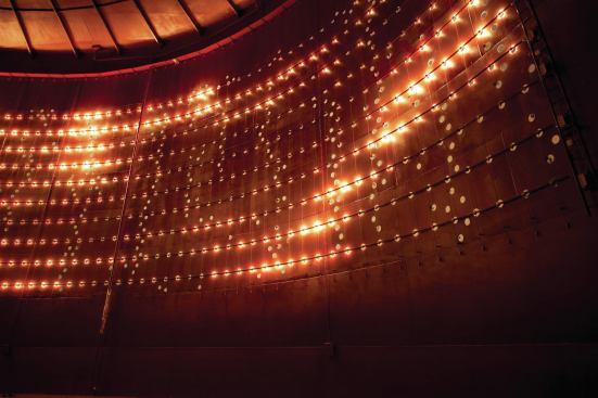 The warm-white LED grid reflects light indirectly behind the perforations. 