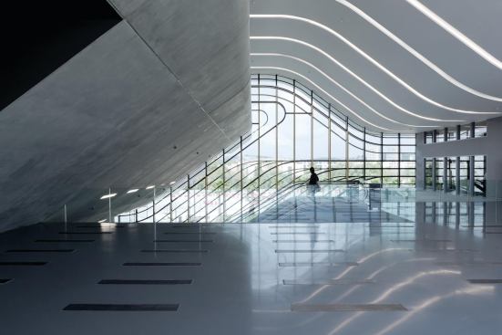 On the second level of Pierresvives, a triple-height lobby features a curving roof incised with cove lighting. 