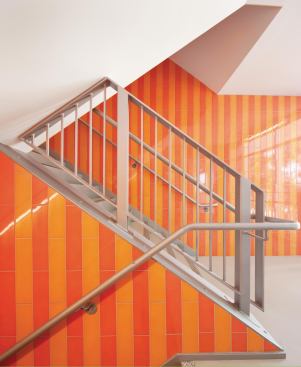 The building’s largely quiet color palette is broken up by a vivid orange internal stair  that serves all levels. 