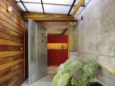 In the dramatic front entry sequence, a long, narrow fish pond borders a walkway shaded by a translucent roof.