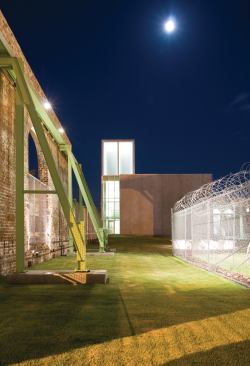 View back toward the SCAD Museum expansion (including the lit tower) from the outdoor event space at night.