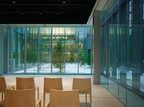 Poets read their work in a performance space, set against the backdrop of a garden. 