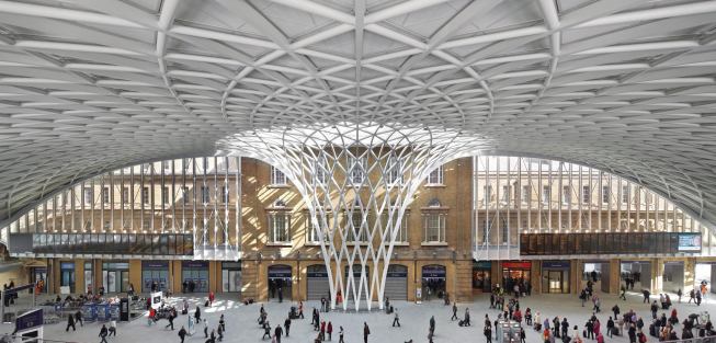 The glass, steel, and aluminum diagrid roof of the new Western Concourse at King’s Cross station spans out from a central woven funnel.