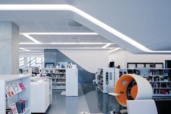 The multimedia library is filled with low stacks that allow views out through the aluminum louver–covered windows.