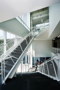 Interior circulation centers on a series of stairs on the west side of the building. The first flight mirrors an outdoor staircase, which doubles as seating for performances. Standing on the second floor landing, students can see up into a courtyard on the third floor.