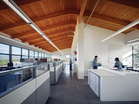 The long, barlike volume of the building is only 38 feet wide, so the interior of the single-story structure is airy and daylit from both sides. This reduces the need for artificial lighting during the day, especially in the relatively densely packed operations area, where there are no walls to inhibit daylight penetration. White walls and neutral finishes highlight the Douglas fir ceiling, which is constructed from tongue-and-groove decking over glulam beams. Often there is so much attention paid to photovoltaics or geothermal as a way of saving energy, Souza says, that low-tech solutions such as these are ignored.