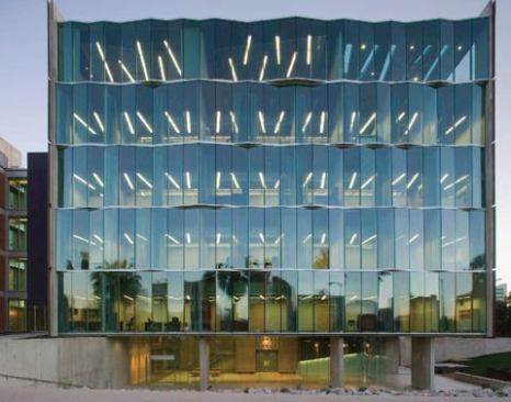 The new addition's north façade, a folded-glass curtain wall, provides views out to the surrounding landscape and abundant natural light into the office and classroom areas by day. Daylight is balanced with T8 fixtures positioned at angles, which correspond to the faceted glass wall. At night, the skewed patterning of the fluorescent tubes takes on a sculptural quality.