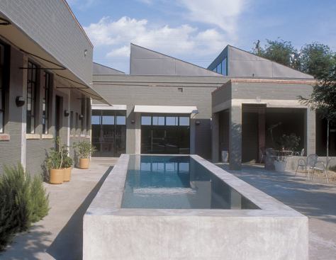 A raised lap pool cools off the courtyard, while the sawtooth roof floods the interiors with light. 