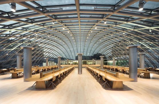 The reading room at the Joe and Rika Mansueto Library at dusk. Directional downlights, fluorescent lighting integrated in the ventilation stacks, and custom-designed reading lamps built into the desks provide the multi-layered lighting strategy.