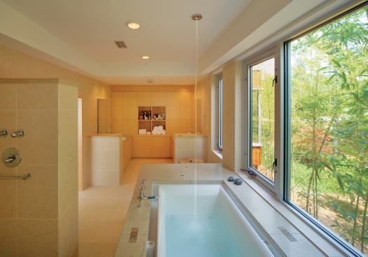 Concrete pieces around the bathtub and on top of partition walls are custom-colored to match the tile. Skillfully composed inserts and cutouts add interest without disturbing the room’s serenity. Maple cabinetry completes a monochromatic, tranquil palette