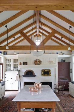 The open-timber kitchen ceiling lets extra sunlight and ventilation pass through the space.