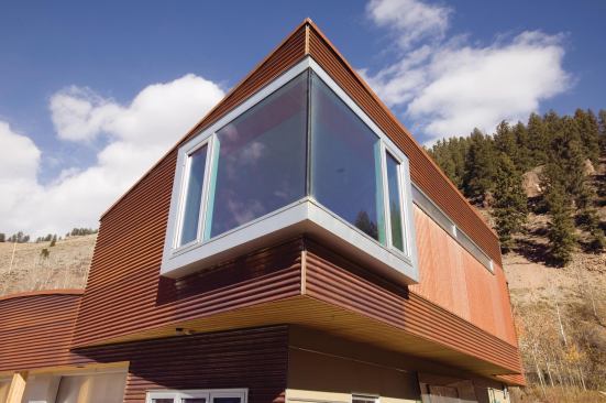 An aluminum-framed corner window contrasts with siding of rusted currugated steel.