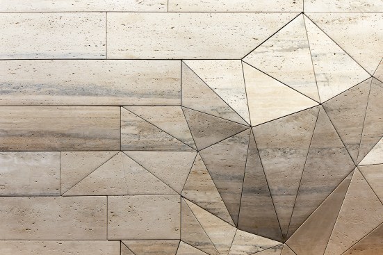 The wall comprises a mixed of honed travertine panels, both filled and unfilled.