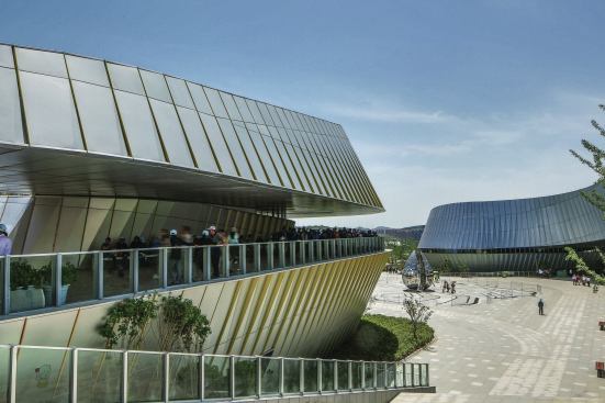 A pathway wraps each building, shaded by the overhanging roof structure. 