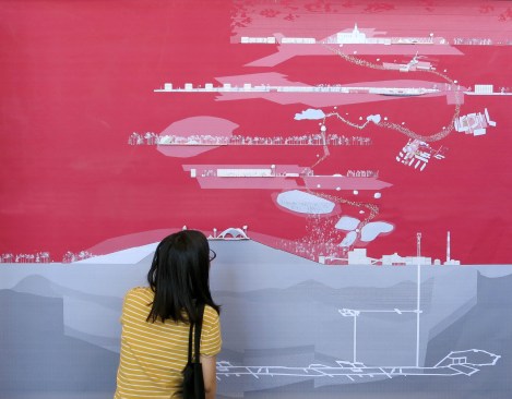 A visitor examines an axonometric route map at an exhibition of the studio's work