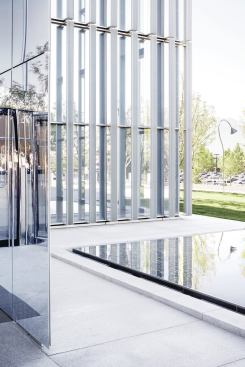 Opposite: A shallow reflecting pool at the southwest corner of the site sits next to the polished stainless steel canopy of the public entrance. Beyond, visitors get a close-up view of the custom extruded and perforated aluminum sunscreen louvers, which are set roughly 15 inches in front of the aluminum curtainwall for optimal shading and daylight penetration, and to accommodate window washing.