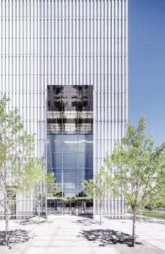 The public entrance at the southwest corner of the site is framed by projecting panels of polished stainless steel. Phifer used this treatment on all of the major openings in the building’s aluminum veil. 